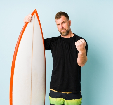 surfer-man-isolated-blue-wall-showing-fist-aggressive-facial-expression